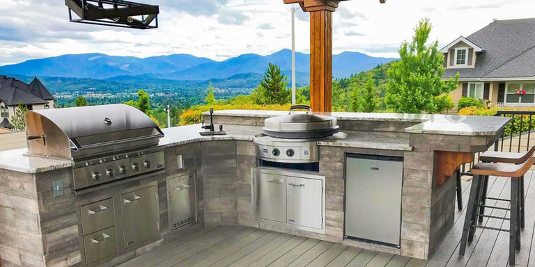An outdoor kitchen with a grill, smoker, refrigerator, storage cabinets, a bar area, and seating 