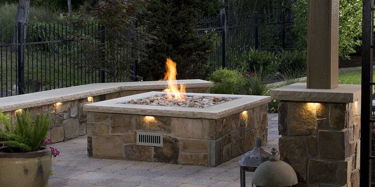 A stone gas fire pit on an outdoor patio 